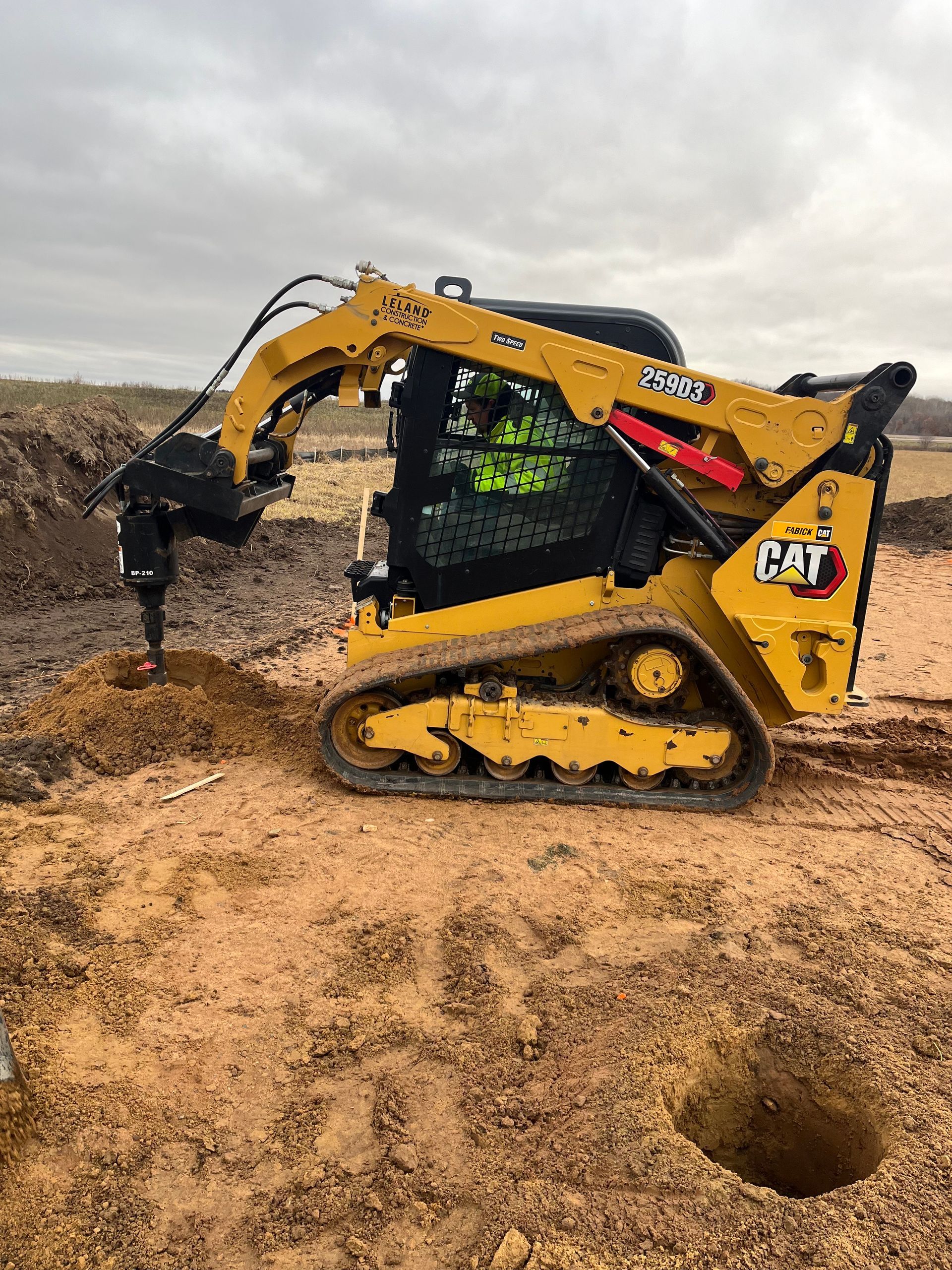 Picture of of an excavator digging holes and preparing the site.