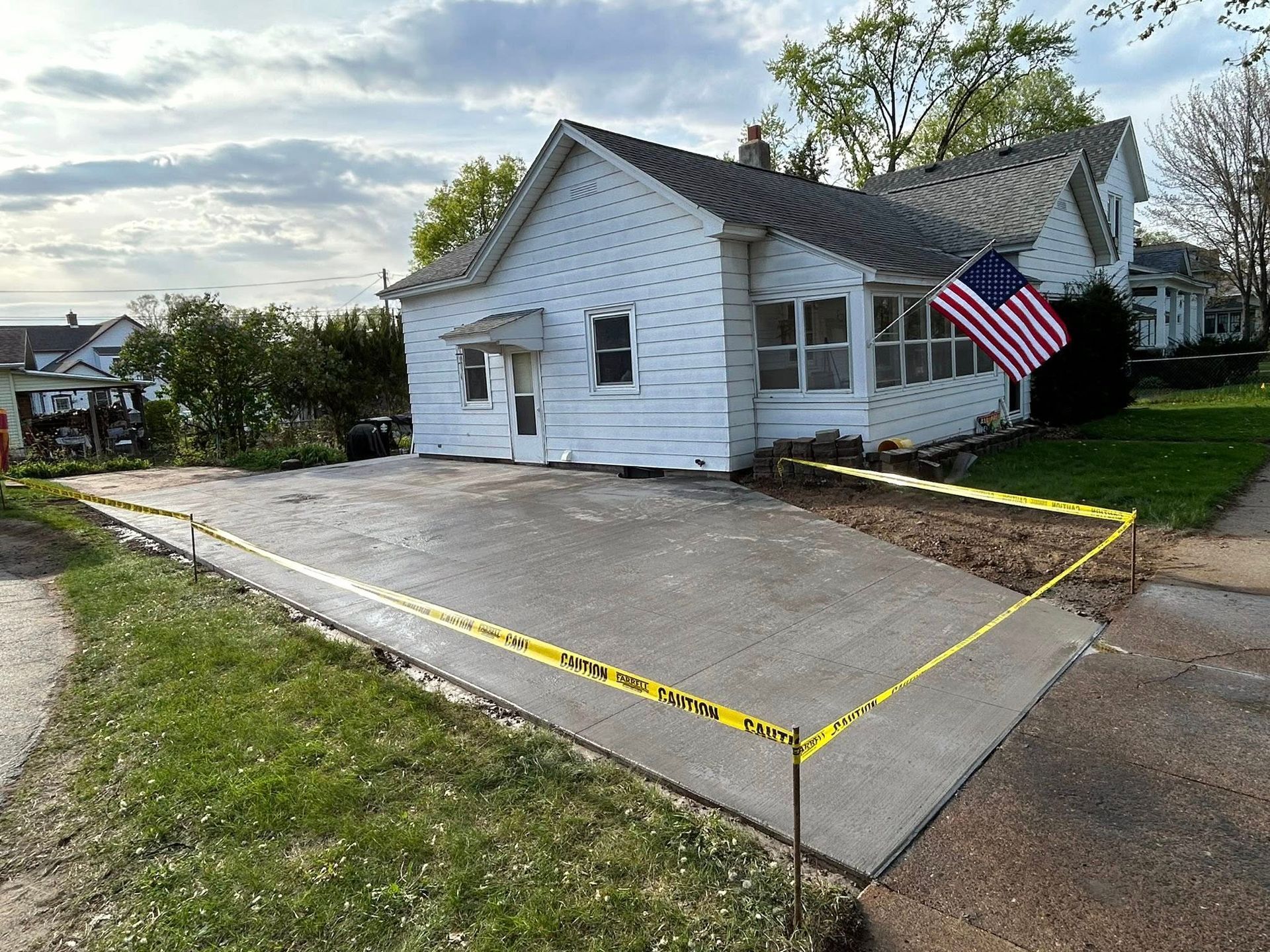 Picture of a driveway expansion for a new house. You can see new concrete drying on the extended sections of the driveway.
