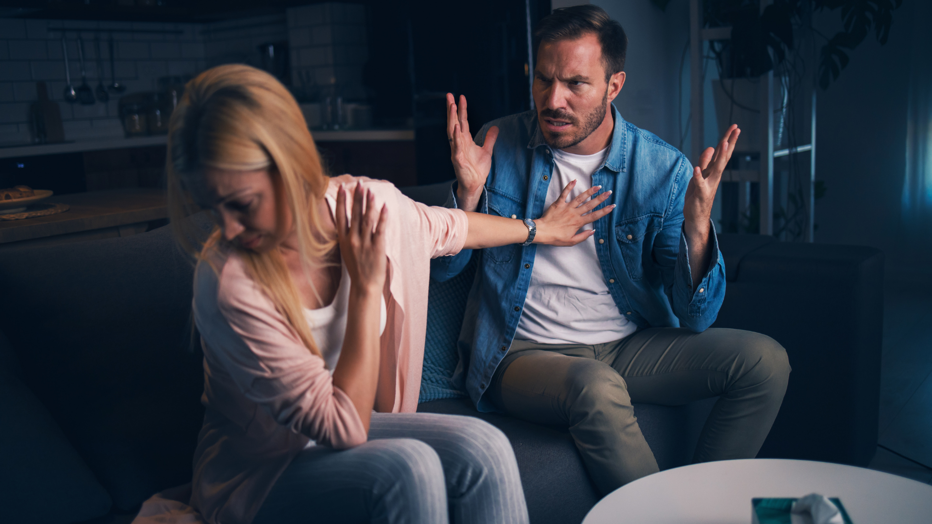 A man and a woman are sitting on a couch having an argument.