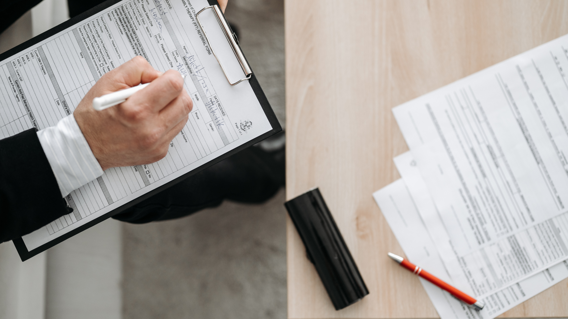 A man is holding a clipboard and writing on it.