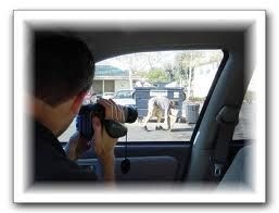 A man is looking through binoculars out of a car window.