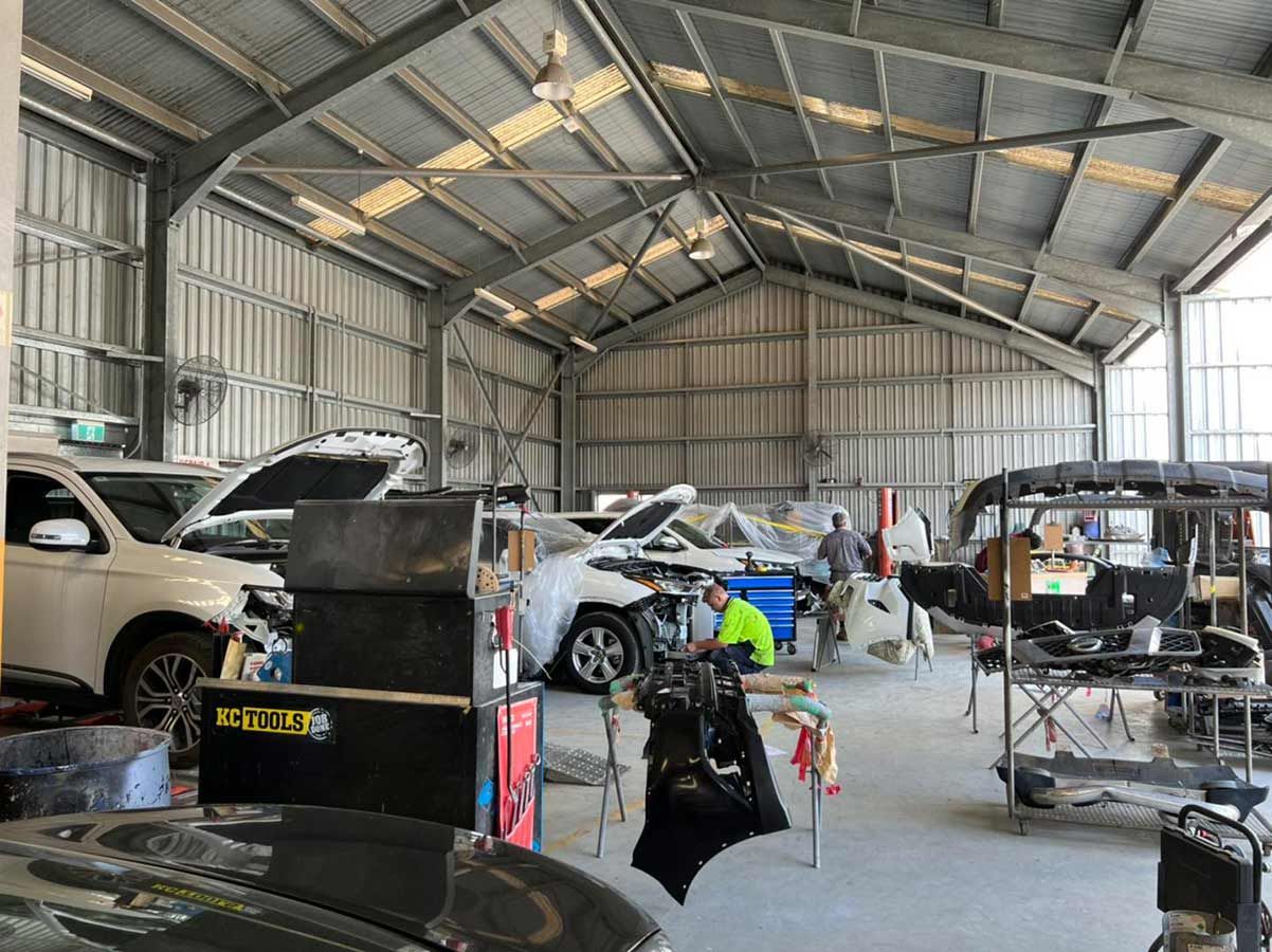 A Garage Filled With Lots Of Cars Being Worked On — Milini's Panel, Paint & Towing in Tully, QLD