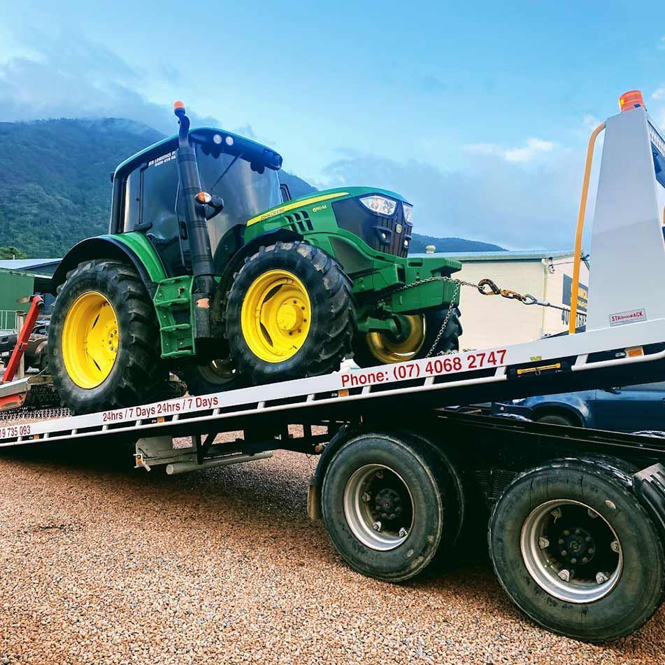 A Green And Yellow Tractor Is Sitting On Top Of A Tow Truck — Milini's Panel, Paint & Towing in Tully, QLD