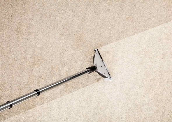 A vacuum cleaner is being used to clean a carpet.