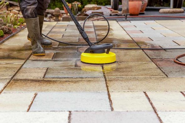 A person is cleaning a patio with a high pressure washer.