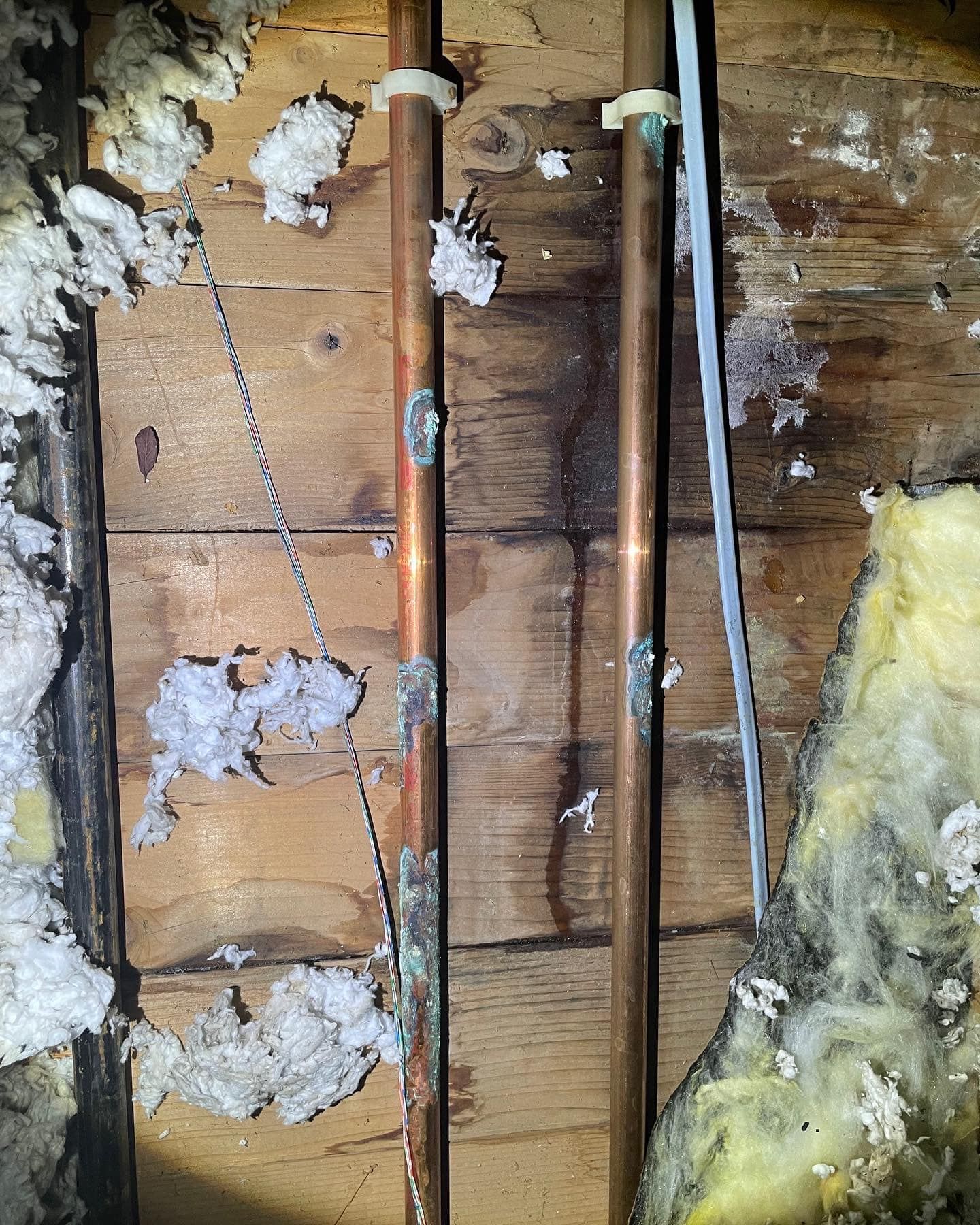 a wooden wall with copper pipes and insulation