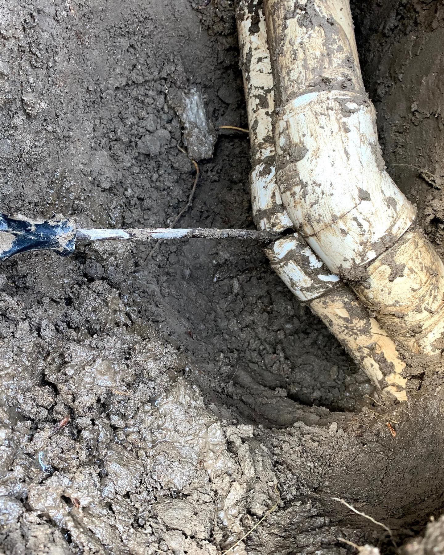 a close up of a pipe in the dirt with a shovel .