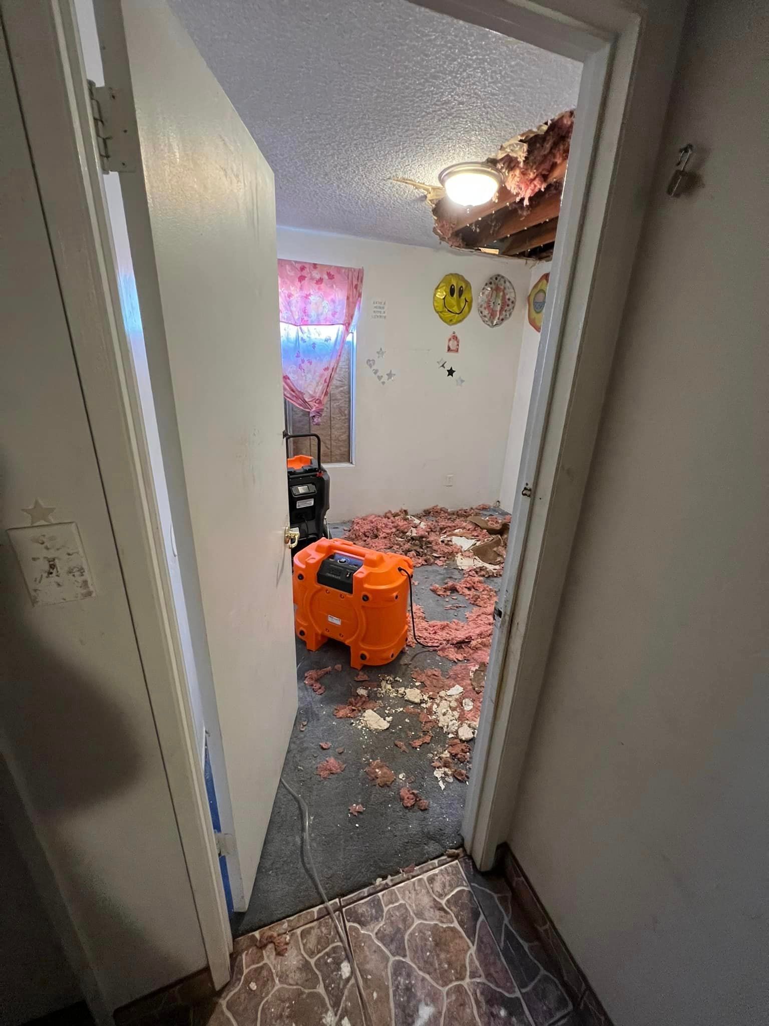 a room with a broken ceiling and a vacuum cleaner on the floor .