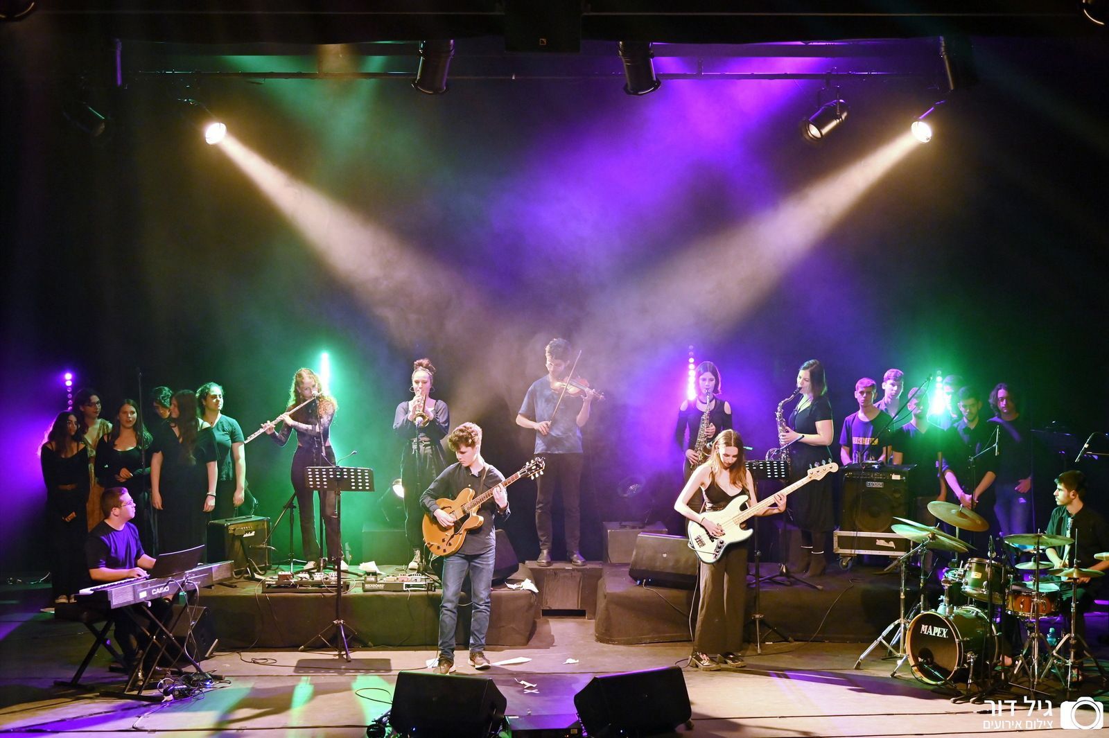 קבוצה של אנשים מנגנים על במה עם אורות סגולים