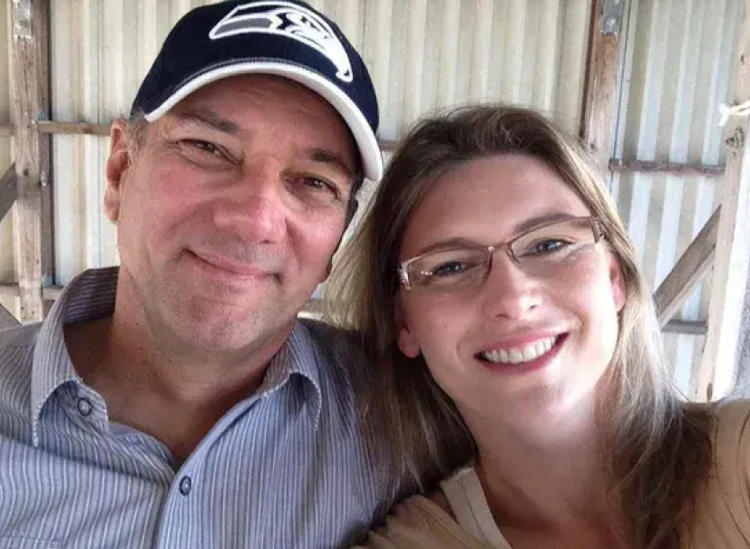 A man with a beard and a name tag on his shirt is standing in a garage. | Mark's Auto Repair