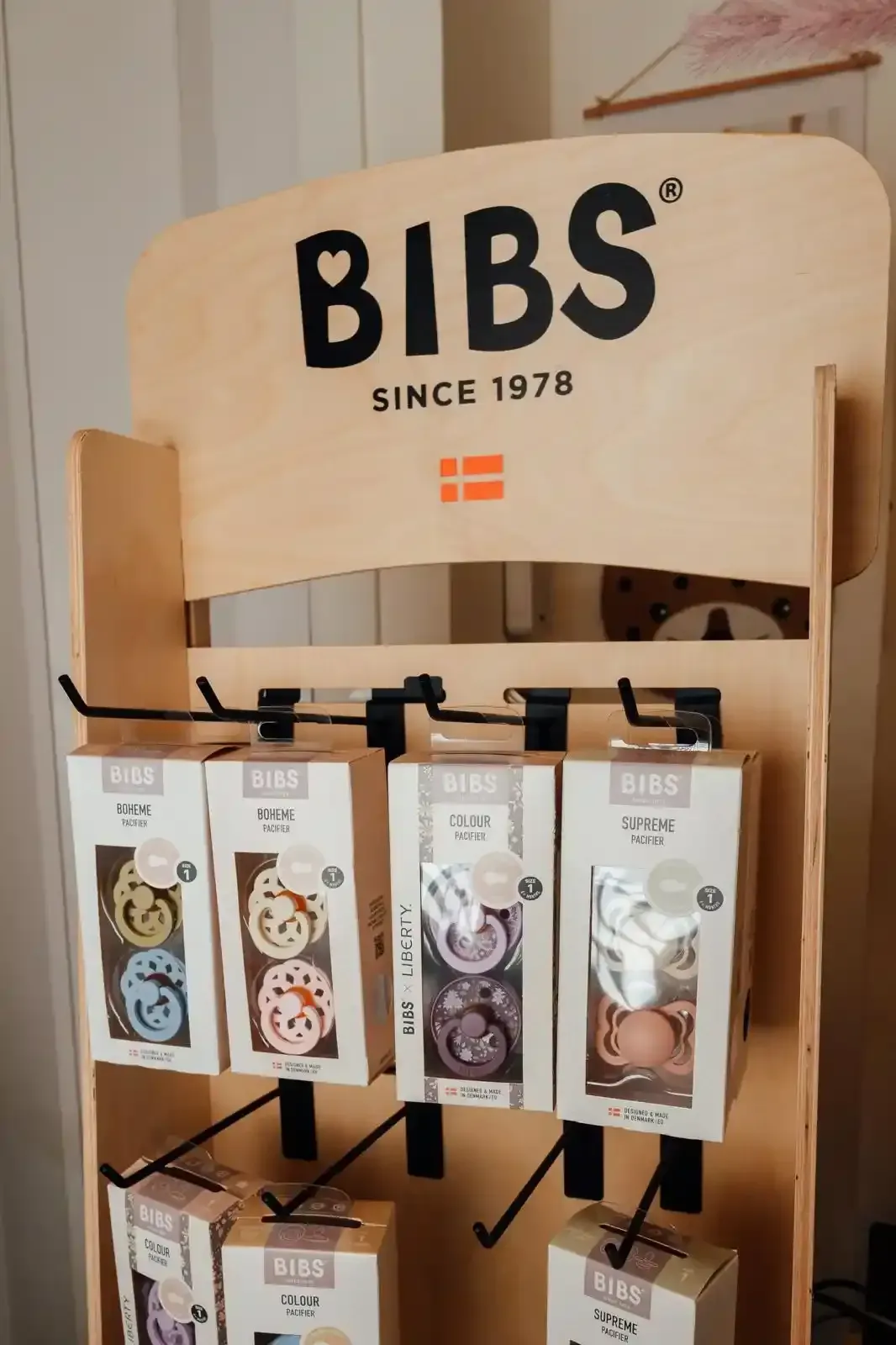 Zaini e stivali da pioggia per bambini a tema dinosauri, nei colori blu, rosa e verde, esposti su un tavolo.