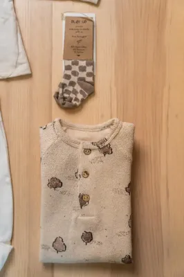 Zaini e stivali da pioggia per bambini a tema dinosauri, nei colori blu, rosa e verde, esposti su un tavolo.