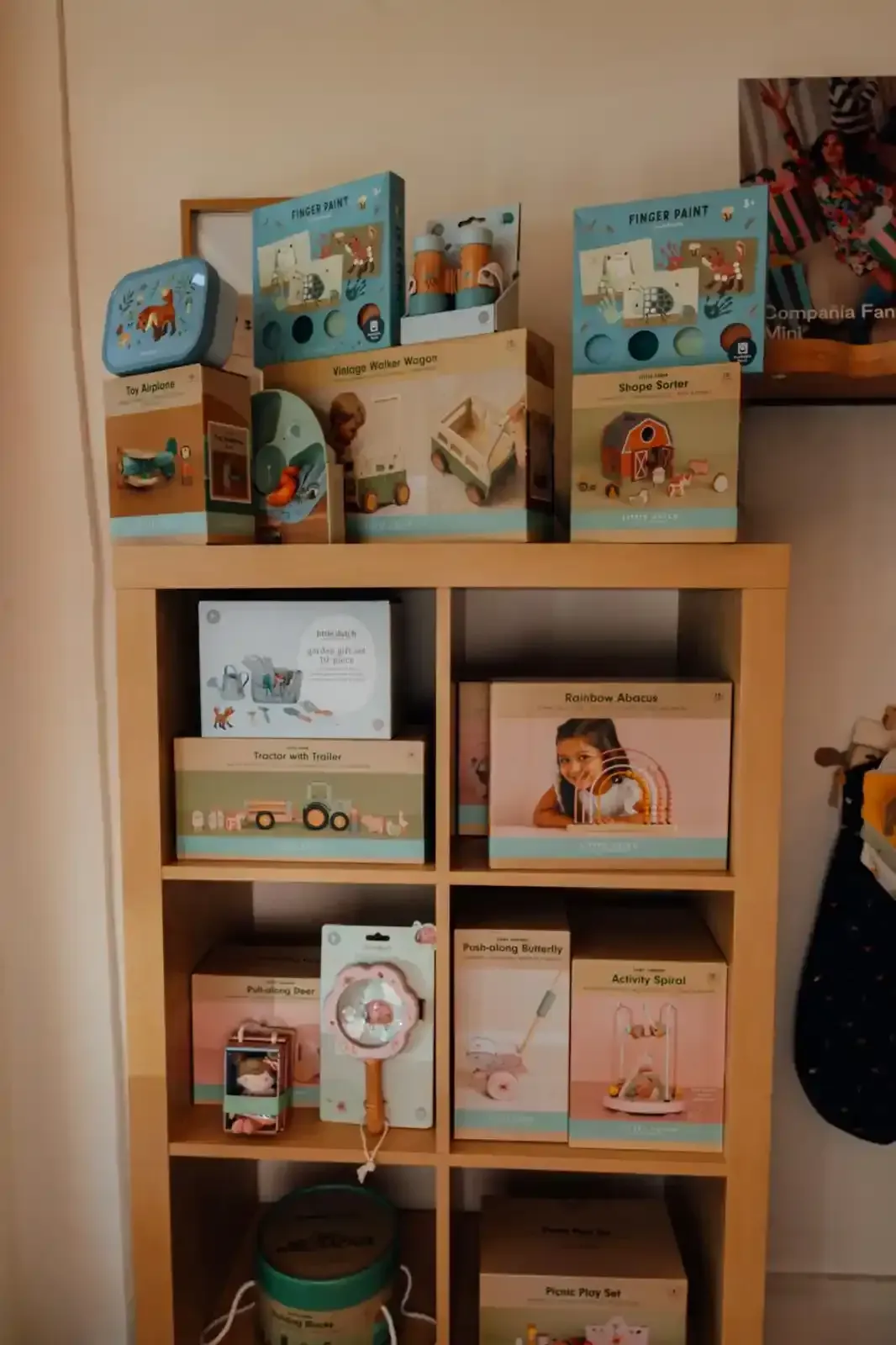 Monopattino giocattolo rosa e in legno con una bambola in una scatola, esposto in un negozio.