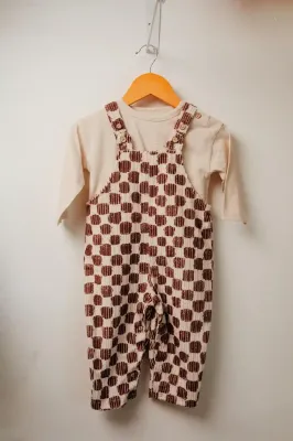Pantaloni di lino bianco e top con stampa geometrica color corallo appesi alle grucce.