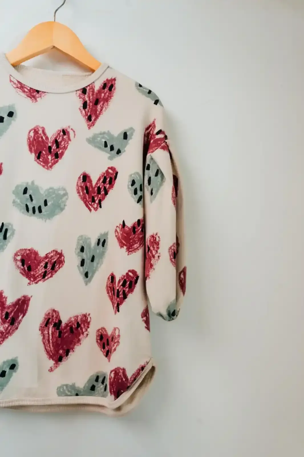 Tre set di pigiami per bambini piegati con diverse fantasie floreali su una superficie di legno.