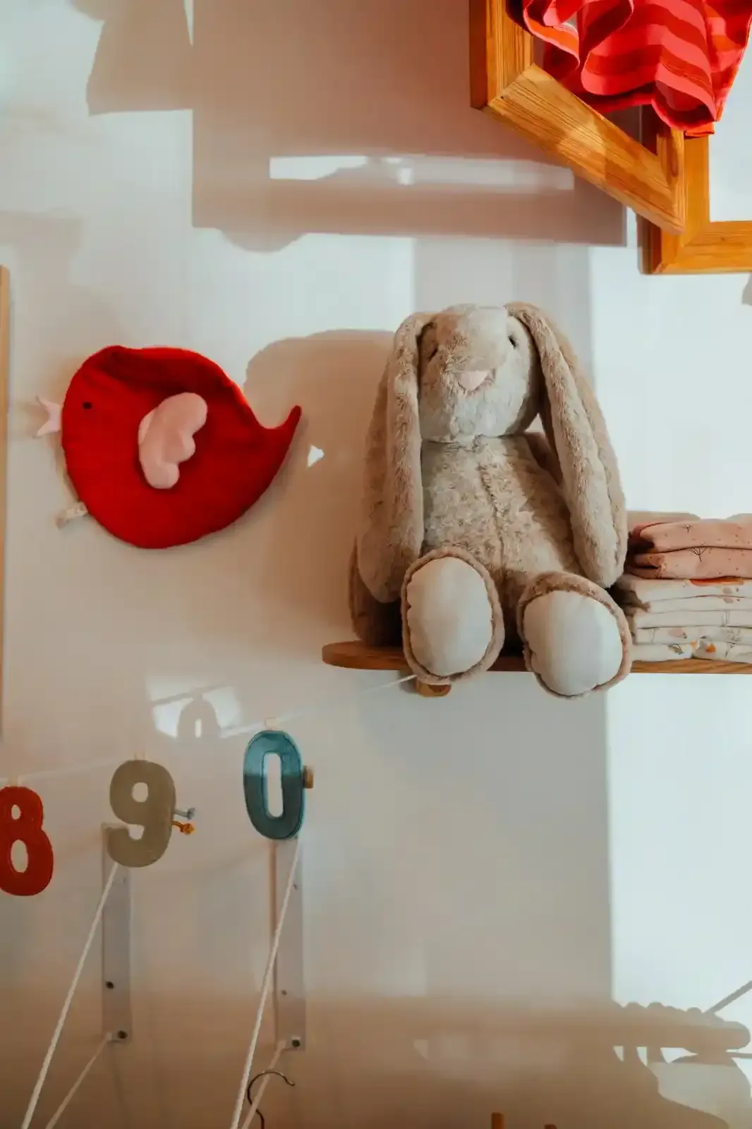 Vestiti appesi su un attaccapanni di legno; sono visibili un vestito rosa con colletto bianco, rifiniture verdi e un maglione grigio.