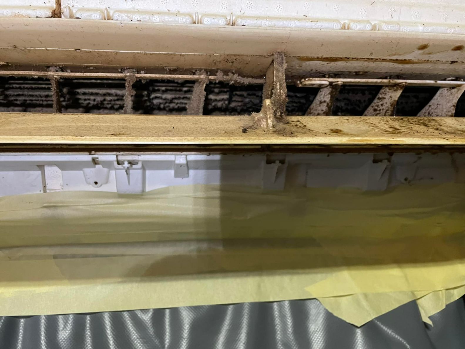 A Close Up of a Dirty Air Conditioner With a Yellow Cloth on the Floor — More Clean Air In Cessnock, NSW