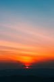 Sunset over mountain silhouettes with vibrant orange and pink hues in the sky.