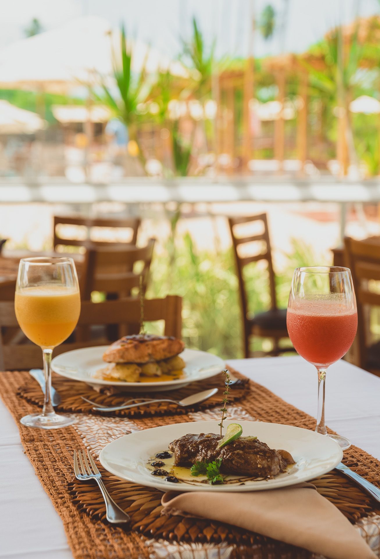 Mesa posta para dois com comida e bebidas, ambiente de restaurante.