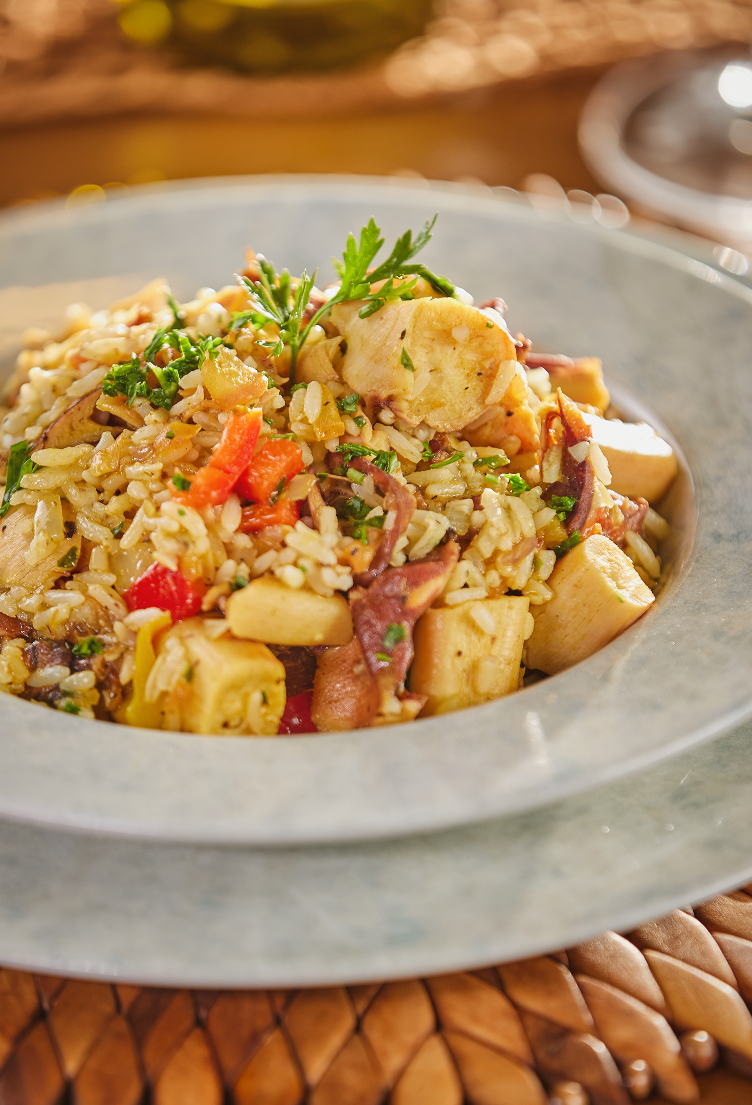 Edifício moderno com fachada de pedra, janelas de vidro e rampa, perto de palmeiras e praia.