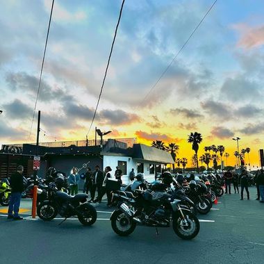 A group of motorcycles are parked in a parking lot at sunset