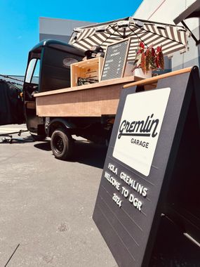 A food truck is parked in a parking lot next to a sign.