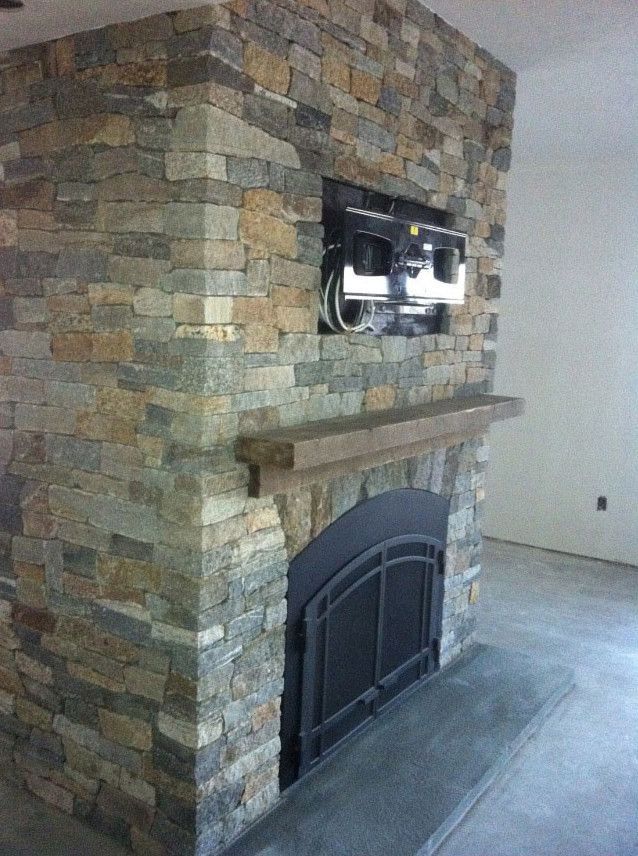 A stone fireplace with a television mounted on the wall above it