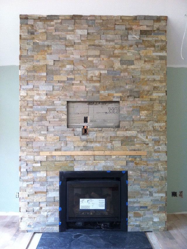 A stone wall with a fireplace in the middle of it