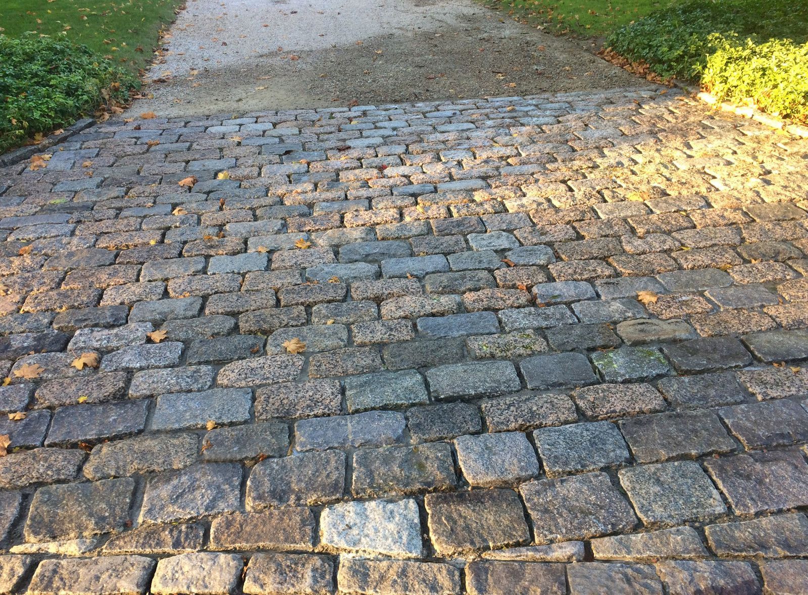 A cobblestone driveway leading to a grassy area
