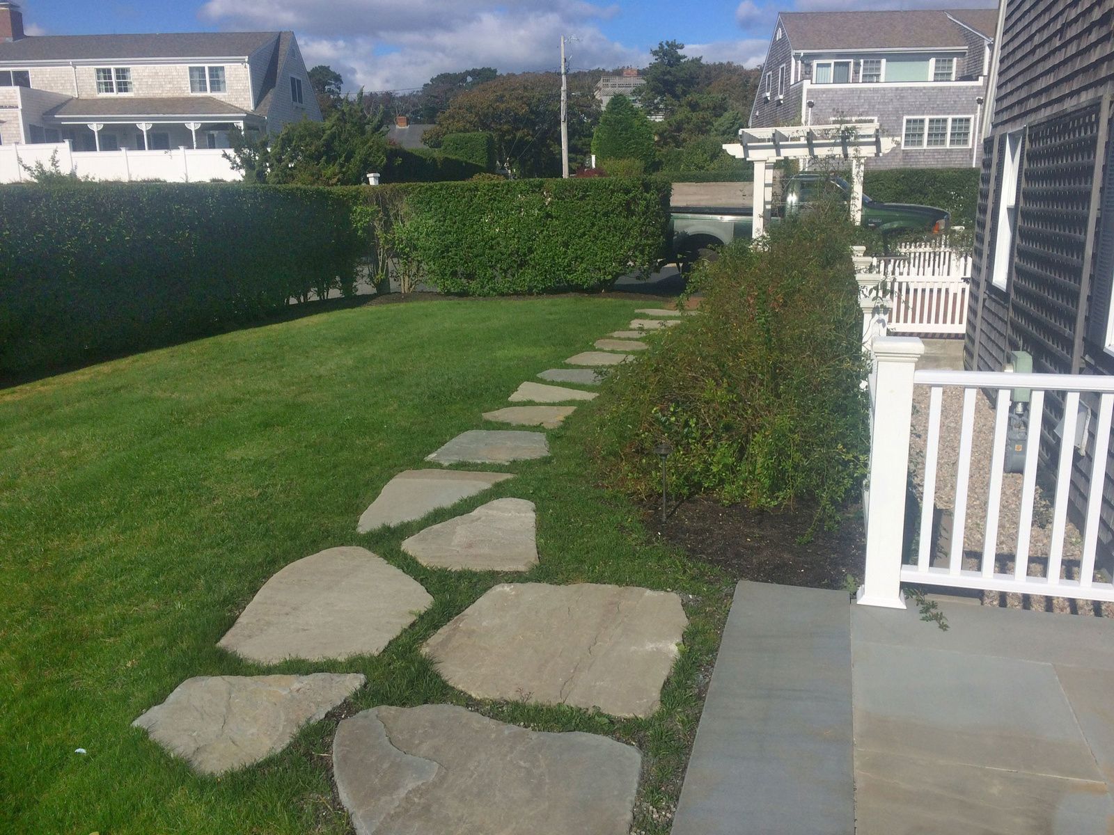 A stone walkway leading to a house with a white railing