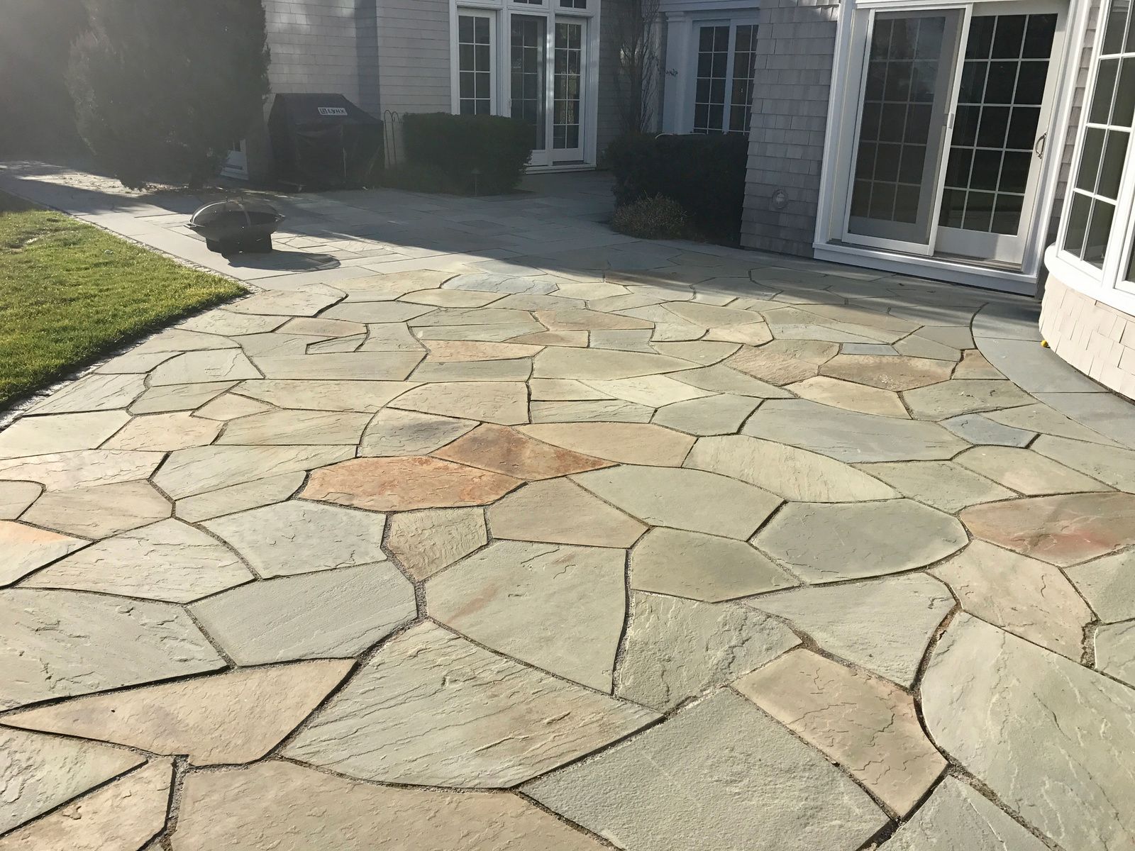 A stone patio in front of a house with a sliding glass door