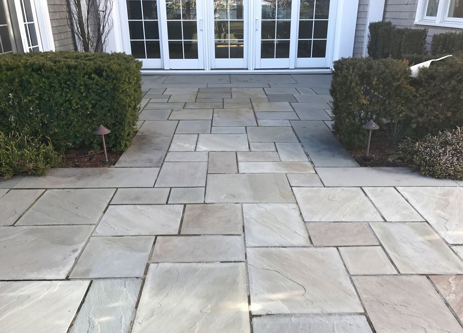A stone walkway leading to a house with sliding glass doors