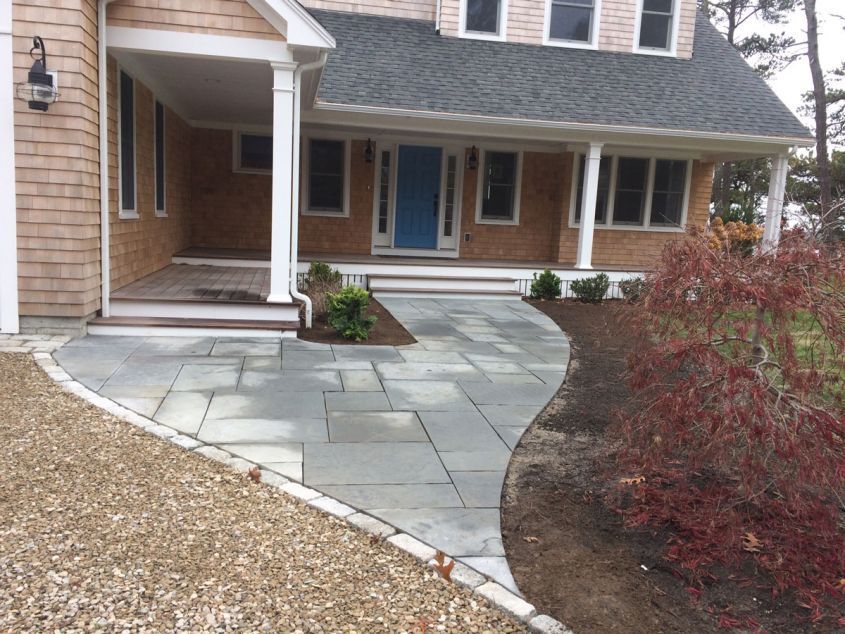 A brick house with a blue door and a walkway leading to it
