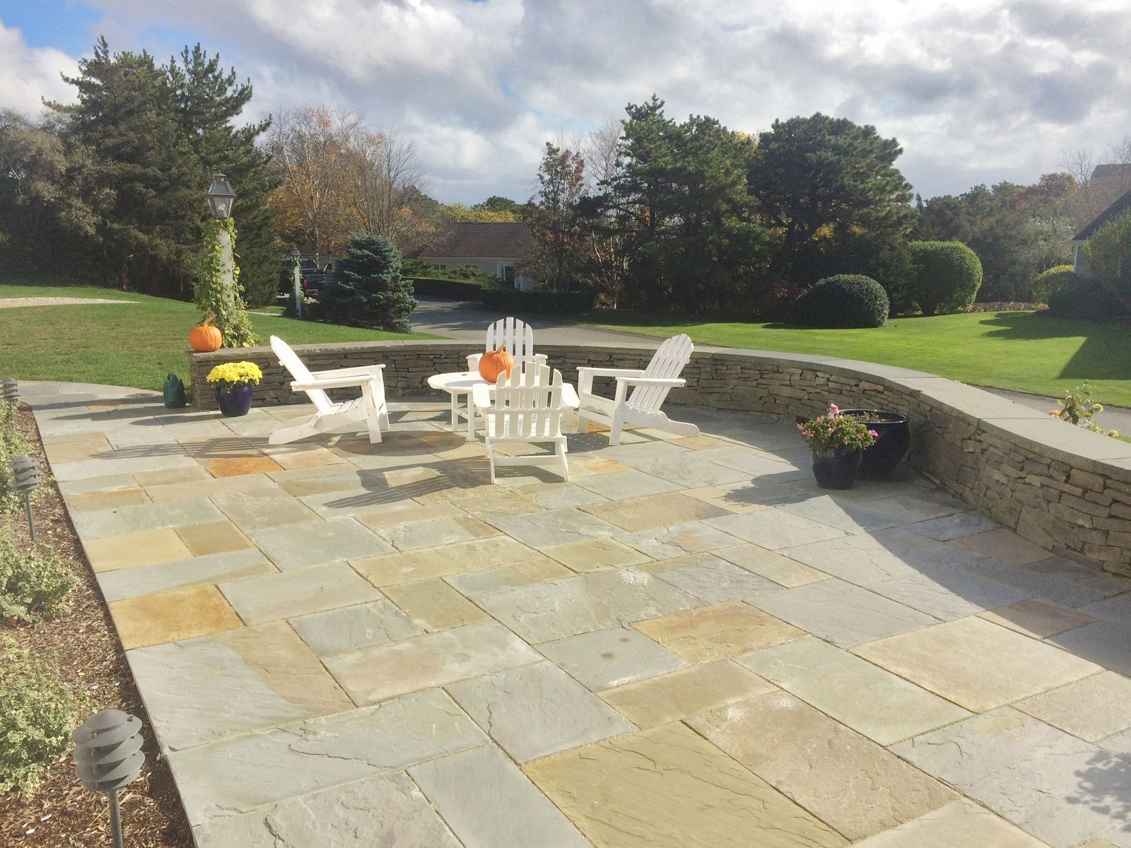 A stone patio with white chairs and a table