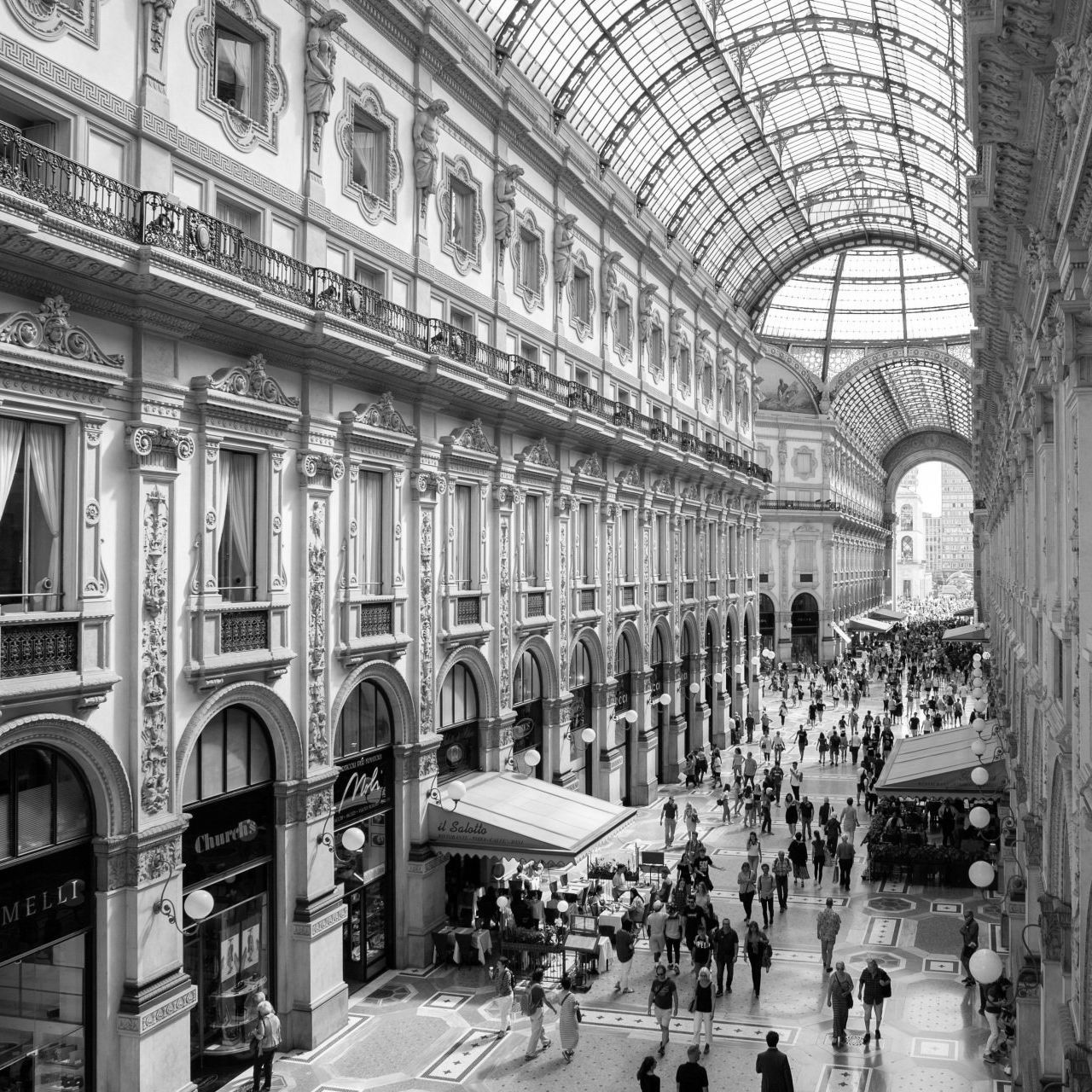 A black and white photo of people walking through a shopping mall.