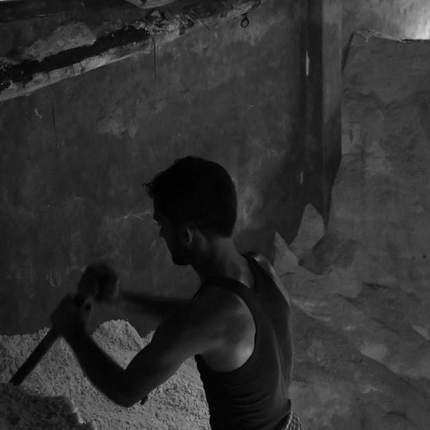 A black and white photo of a man holding a hammer.