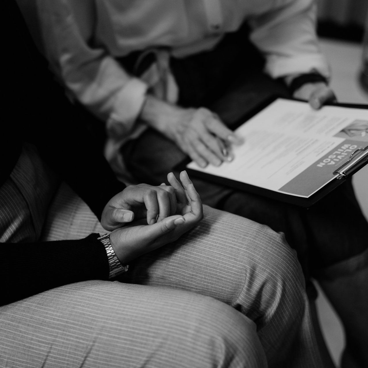A black and white photo of two people holding hands