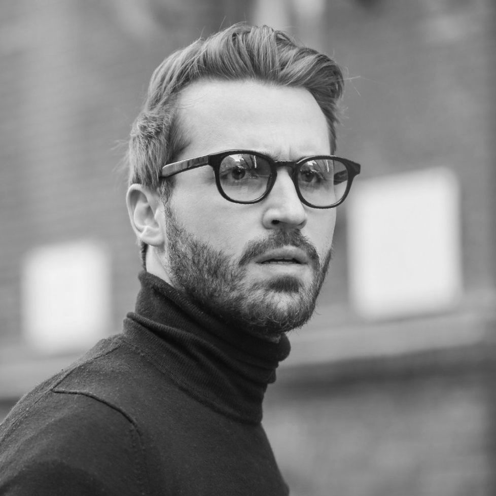 A man with a beard wearing glasses and a black turtleneck.