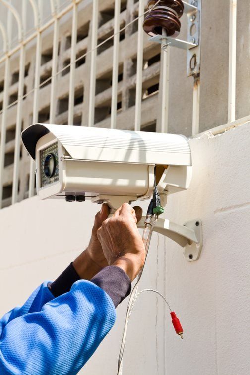 Security Camera Mounted On Exterior Wall Being Connected — Barnes Electrical in Mackay, QLD