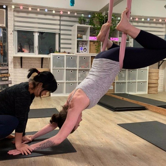 Miss Lydia is adjusting student in private aerial yoga class