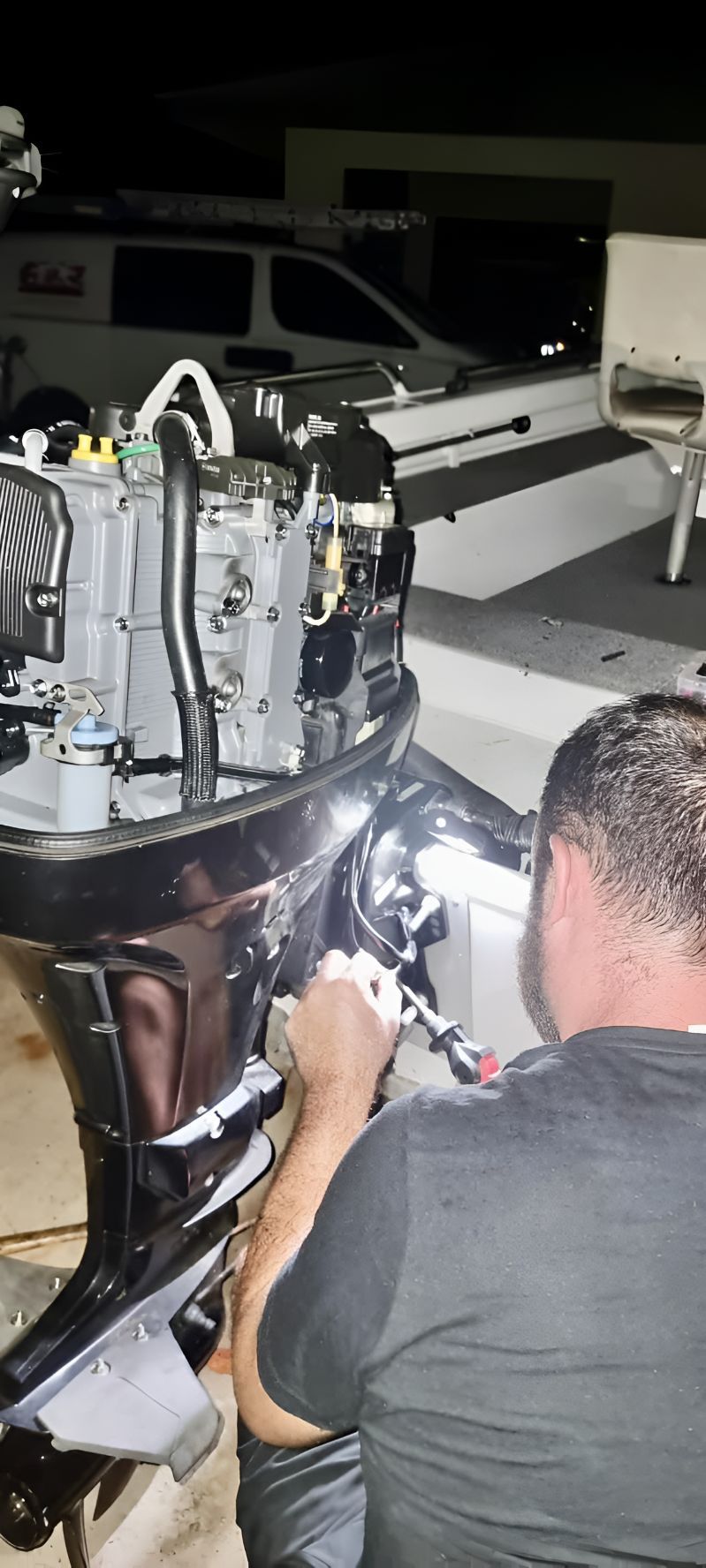 A Man Is Working On A Boat Engine At Night — Deri's Mobile Mechanical In Parap, NT
