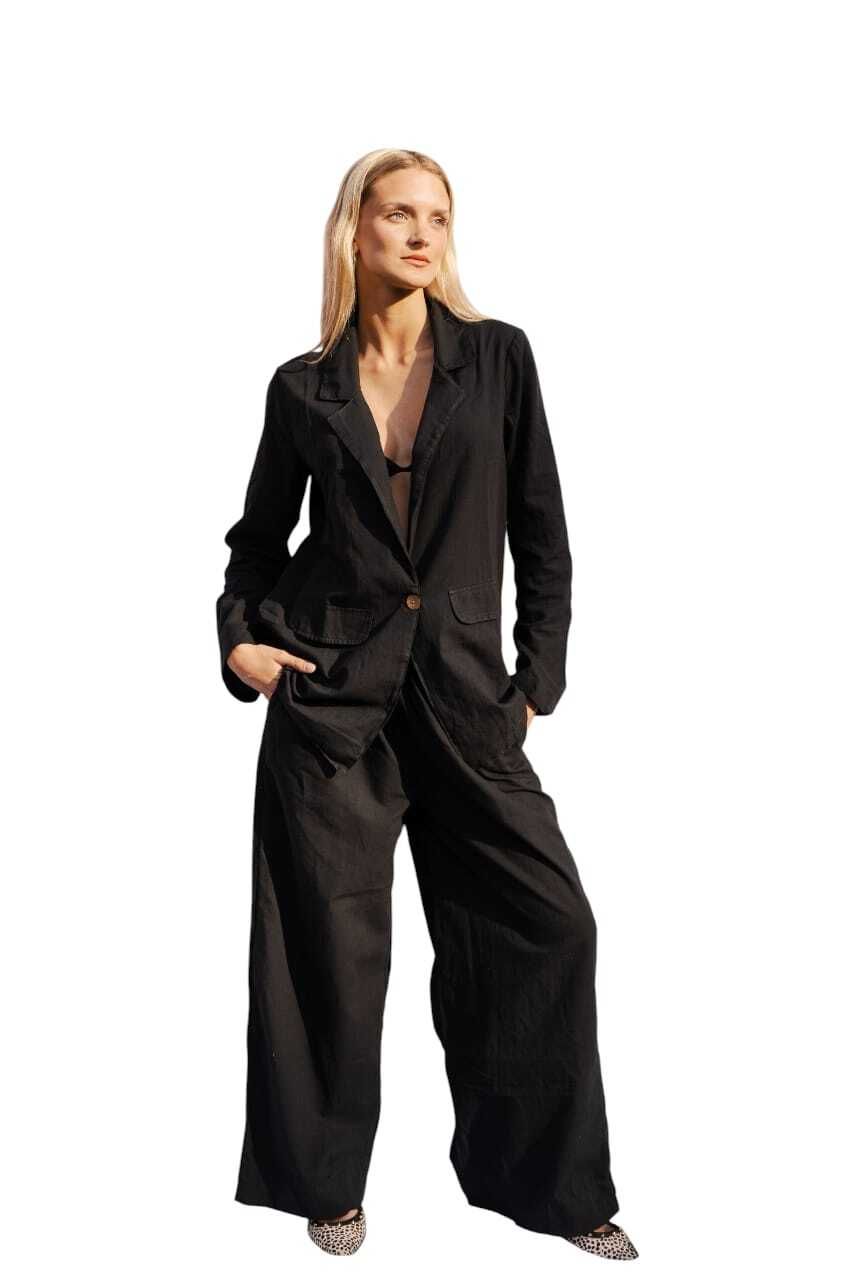 Mujer con mono negro, manos en los bolsillos, mirando hacia arriba.