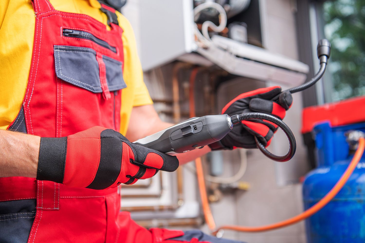 Close-up of a technician using a gas detector device, looking for a gas leak.