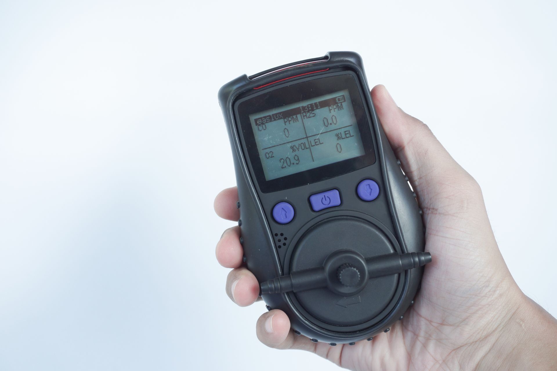 Close-up of a hand holding a black portable gas detector.