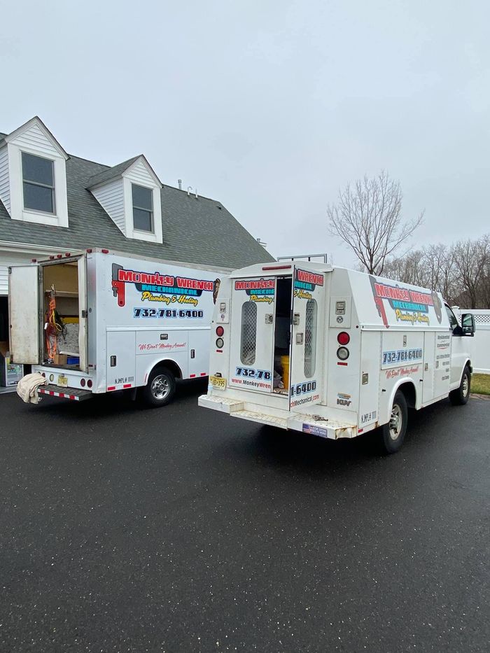 Two utility trucks are parked in front of a house.