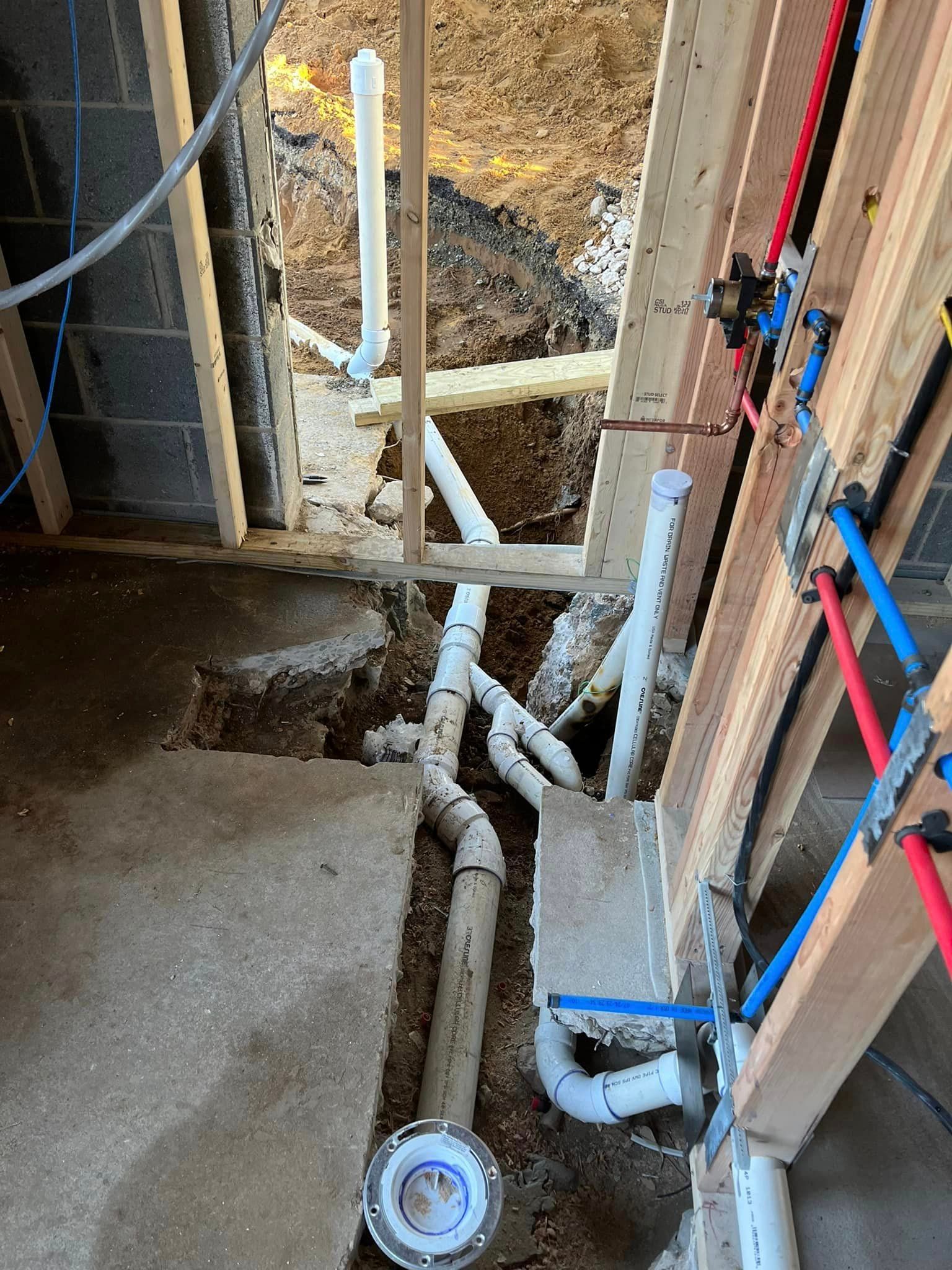 A bathroom under construction with a lot of pipes coming out of the ground.