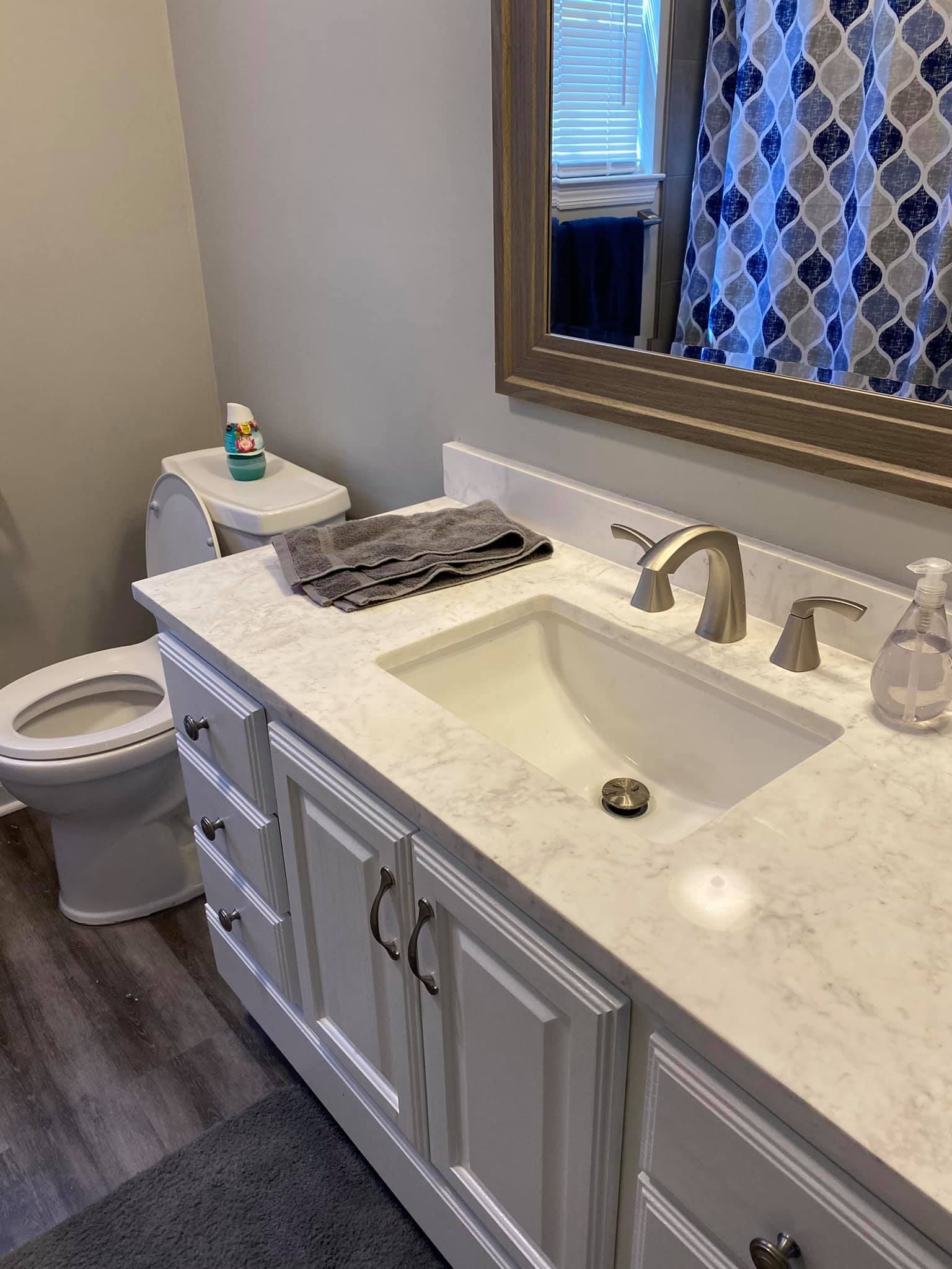 A bathroom with a sink , toilet and mirror.