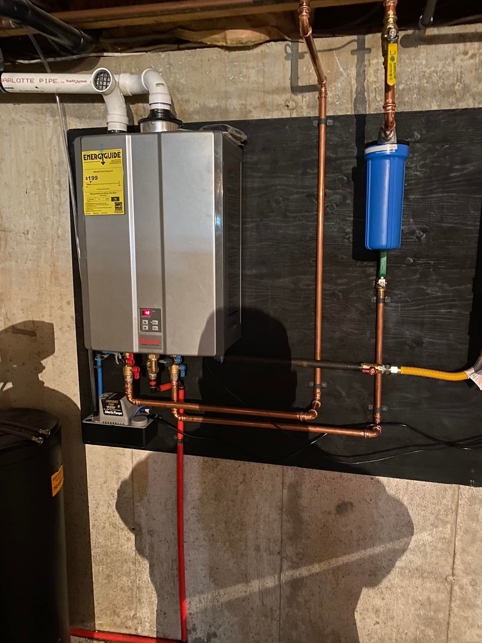 A water heater is installed in a basement next to copper pipes.