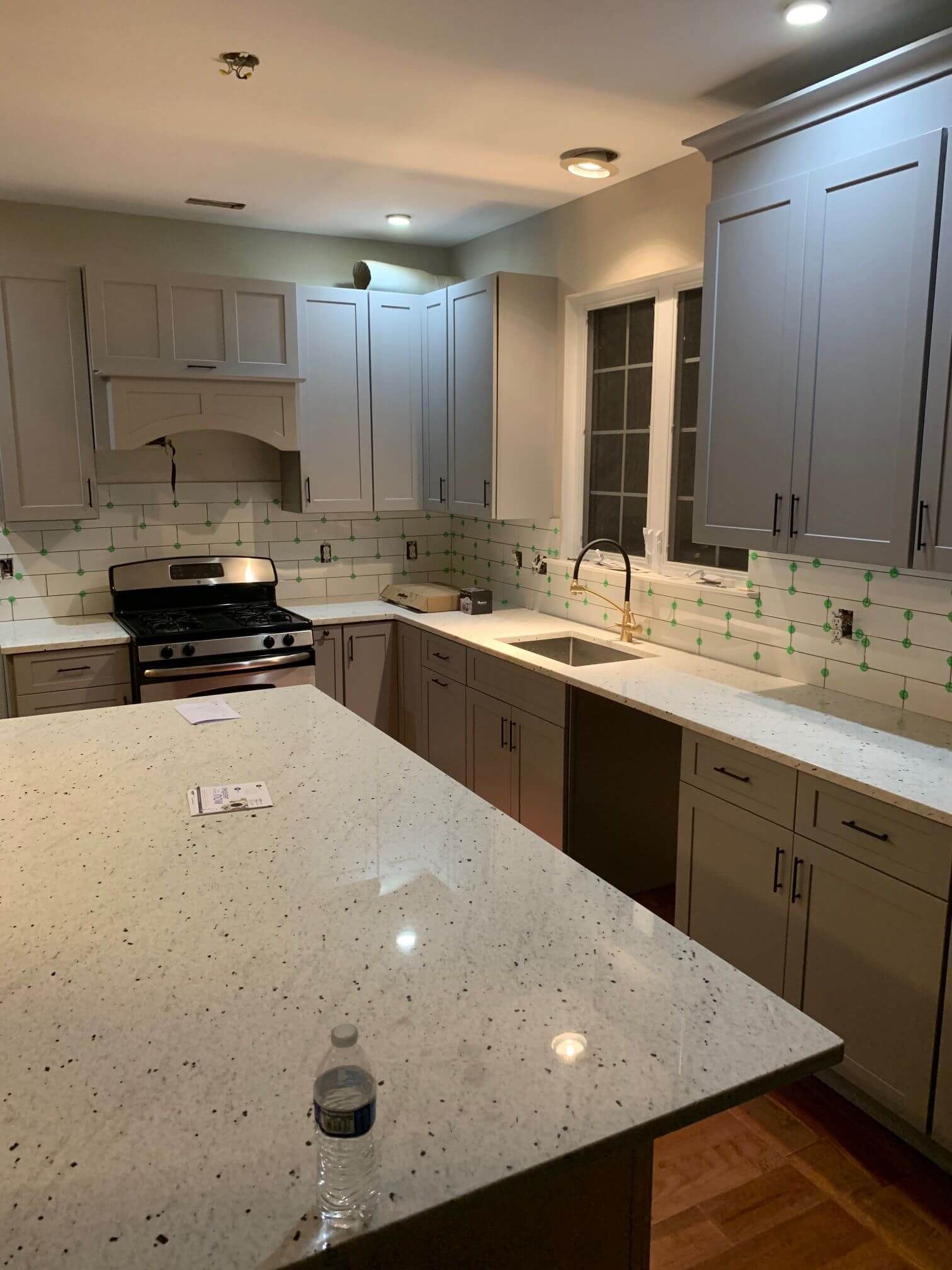 A kitchen with white cabinets and a large island with a bottle of water on it.