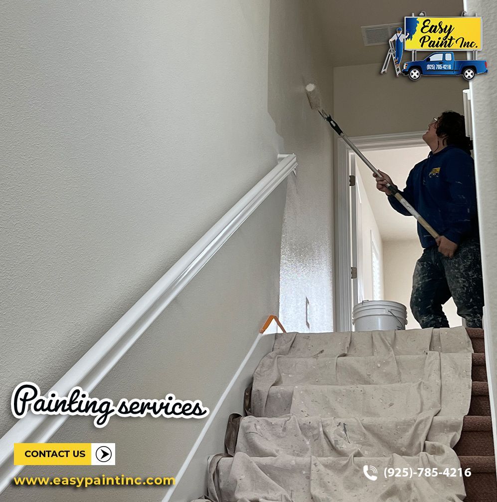Person painting a staircase wall with a roller.  White paint, protective covering on steps.  Easy Paint Inc. logo.